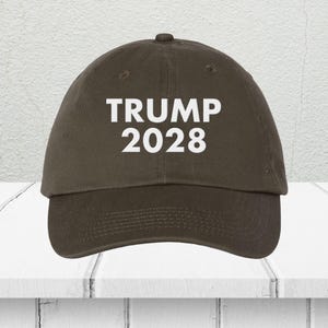 Pode incluir: Um bon&eacute; de beisebol marrom com texto branco que diz "TRUMP 2028".
