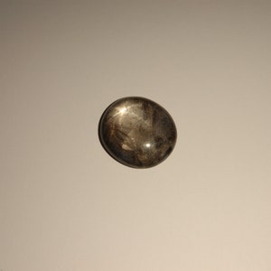 Könnte beinhalten: Ein glatter, ovaler, dunkelgrauer Edelstein mit einer reflektierenden Oberfläche.