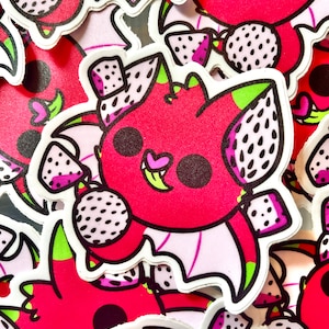 Op de afbeelding: Een verzameling stickers met een cartoon drakenvrucht karakter. De stickers zijn voornamelijk rood met witte, zwarte, groene en roze accenten. Het drakenvrucht karakter heeft een lachend gezicht, vleugels en houdt een drakenvrucht vast.