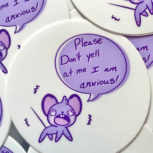 Può includere: Un set di adesivi rotondi bianchi con l'illustrazione di un topo dei cartoni animati. Il topo viola ha un'espressione preoccupata e una nuvoletta con il testo: "Please don't yell at me I am anxious!"