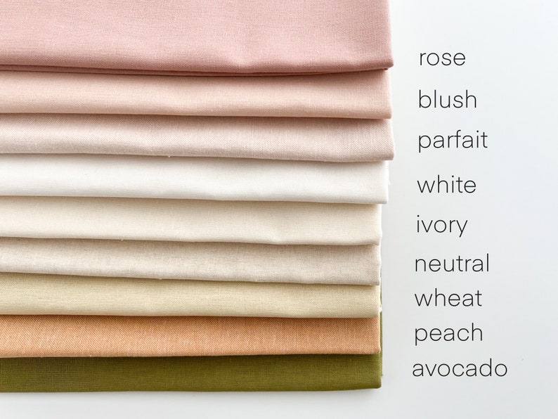 May include: A stack of ten fabric swatches in various shades of pink, white, beige, brown, and green. The swatches are labeled with the following colors: rose, blush, parfait, white, ivory, neutral, wheat, peach, and avocado.