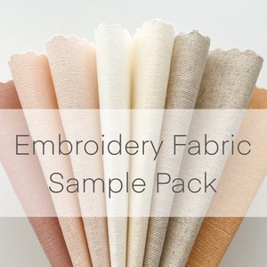 May include: A sample pack of embroidery fabric in various shades of beige, brown, and white. The fabric is rolled up and arranged in a fan shape. The text "Embroidery Fabric Sample Pack" is printed on a white label.