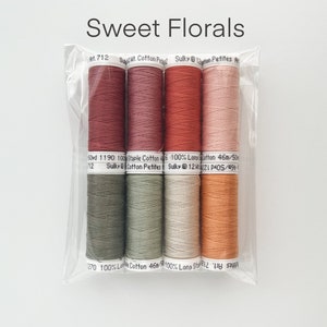 May include: Six spools of thread in various shades of red, orange, green, and beige. The thread is labeled "Sulky Cotton Petites" and "100% Long Staple Cotton".