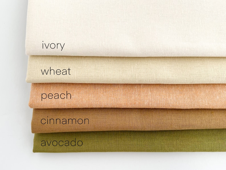 May include: Five fabric swatches stacked on top of each other. The swatches are ivory, wheat, peach, cinnamon, and avocado.