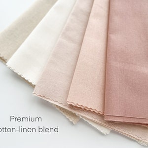 May include: A close-up of five fabric swatches in various shades of beige and pink. The swatches are arranged in a fan shape and have a slightly textured surface. The text "Premium cotton-linen blend" is printed below the swatches.