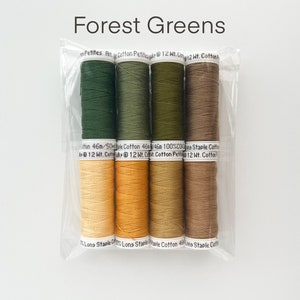 May include: A package of six spools of thread in shades of green and brown. The spools are labeled "Petites Pit Cotton Petite 12 Wt. Cotton" and "Long Staple Cotton 46m/50m 100% Cotton 12 Wt. Cotton".
