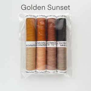 May include: A set of six spools of thread in shades of orange, brown, and black. The thread is labeled "Golden Sunset" and is packaged in a clear plastic bag. Art. 712-1825lt. Cotton Petite 12 Wt. Cotton 234 Sulky 12 50 Staple Cotton Line Staple Cotton Cotton Petite Art. 712 50yd/46 Sulky@12 Staple Cotton Whole Cotton 46 50rd 1128 008 100% Long.