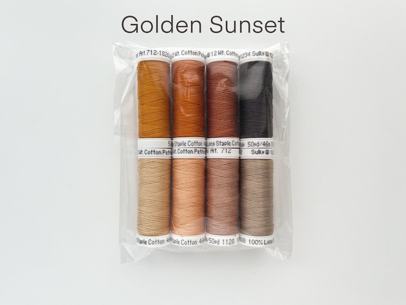 May include: A set of six spools of thread in shades of orange, brown, and black. The thread is labeled "Golden Sunset" and is packaged in a clear plastic bag. Art. 712-1825lt. Cotton Petite 12 Wt. Cotton 234 Sulky 12 50 Staple Cotton Line Staple Cotton Cotton Petite Art. 712 50yd/46 Sulky@12 Staple Cotton Whole Cotton 46 50rd 1128 008 100% Long.