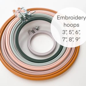 May include: A collection of embroidery hoops in various sizes and colors, including brown, pink, green, and gray. The image includes hoops sized 3", 5", 6", 7", 8", and 9", perfect for embroidery projects.