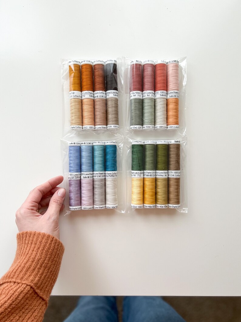 May include: Assortment of 20 spools of 100% cotton thread in various colors, including shades of brown, green, blue, and yellow. Each spool is labeled with the brand name "Sulky" and the thread weight "12wt".