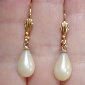 Puede incluir: Un par de pendientes de oro con piedras de color blanco nacarado en forma de lágrima.