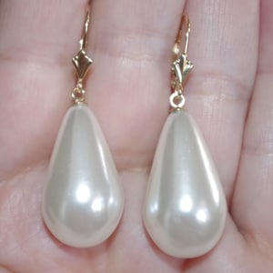 May include: A pair of gold teardrop earrings with large white pearlescent drops.