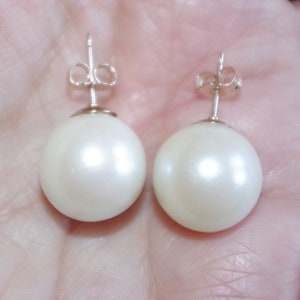 May include: A pair of white pearl stud earrings with silver posts.