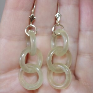 May include: A pair of gold dangle earrings with three linked translucent green jade circles.