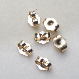 Peut inclure: Six dos d'oreille dorés. Les dos sont en forme de larme avec un petit trou au centre. Ils sont conçus pour être utilisés avec des boucles d'oreilles à tige.