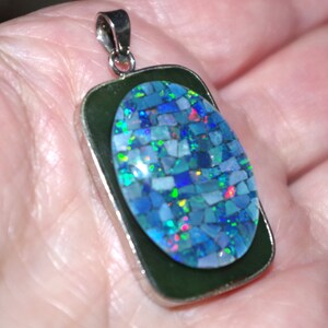 Op de afbeelding: Een zilveren hanger met een groene steen en een blauwe opaal mozaïek inleg.