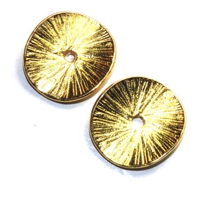 Puede incluir: Dos adornos redondos decorativos de metal de color dorado con un diseño de rayos de sol y un agujero en el centro.
