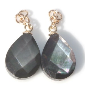 May include: A pair of teardrop-shaped black iridescent earrings with gold jump rings.