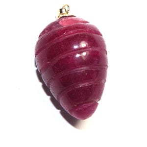 Könnte beinhalten: Ein tief roter, facettierter, tropfenförmiger Anhänger mit einer goldenen Öse.