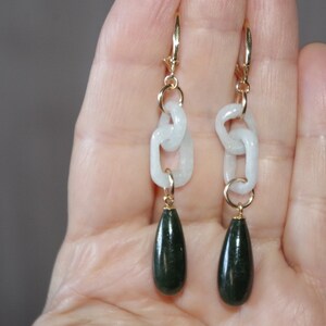 May include: A pair of dangle earrings with a white jade chain and a dark green jade teardrop pendant.