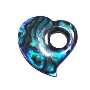 Op de afbeelding: Een hartvormige hanger gemaakt van iriserende abalone-schelp met een gat in het midden. De schelp heeft een blauw, groen en zwart kleurpatroon.