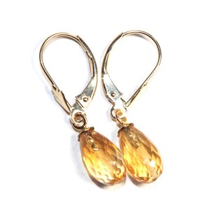 May include: A pair of gold earrings with teardrop-shaped topaz gemstones. The earrings have leverback closures.