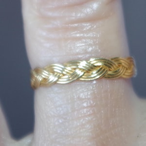 Puede incluir: Un anillo de oro trenzado con un diseño tejido.