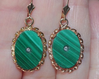 May include: A pair of gold earrings with oval-shaped green malachite stones and a small diamond accent in the center of each stone.