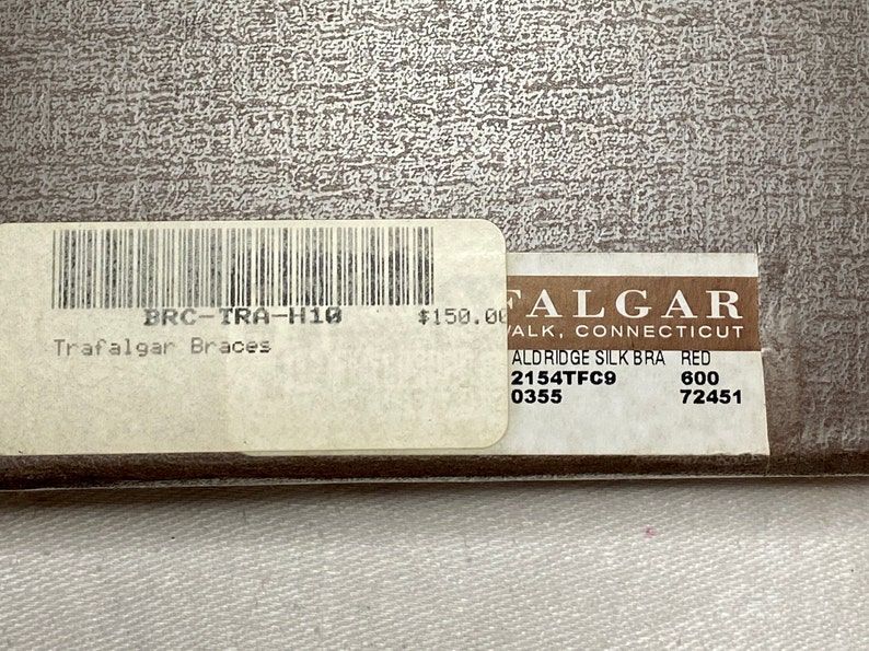 May include: A close-up of a product tag with the text "Trafalgar Braces" and "ALDRIDGE SILK BRA RED". The tag also includes a barcode and the price of $150.00.