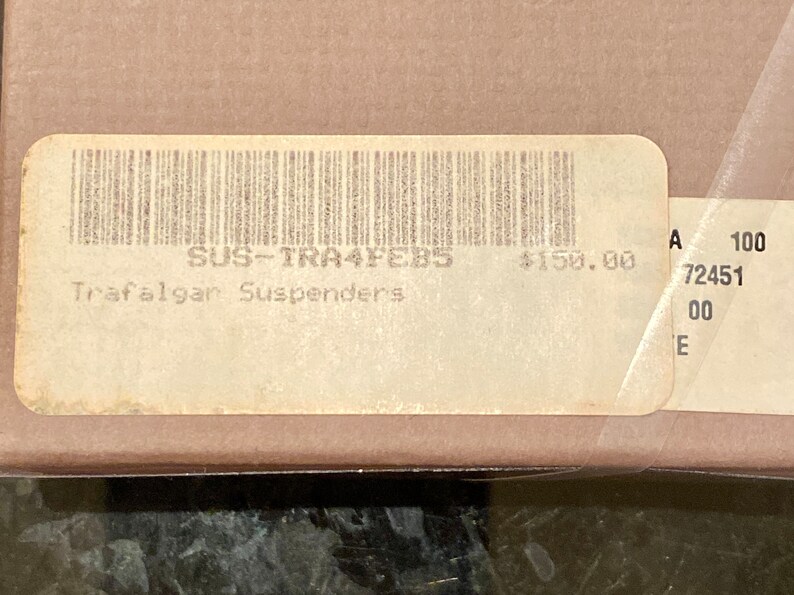 May include: A close-up of a label with a barcode and the text "Trafalgar Suspenders". The label is on a cardboard box. The label also has the text "SUS-TRA4FEB5".