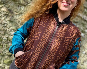 May include: A brown bomber jacket with a teal blue patterned design on the sleeves. The jacket has a zipper closure and two pockets.