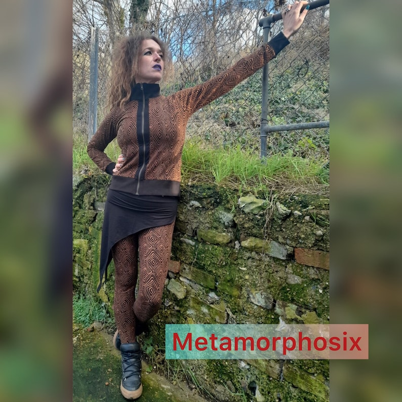 May include: A woman wearing a brown and black geometric patterned jacket and matching leggings. She is standing in front of a brick wall with green moss growing on it. The text "Metamorphosix" is visible in the lower right corner of the image.