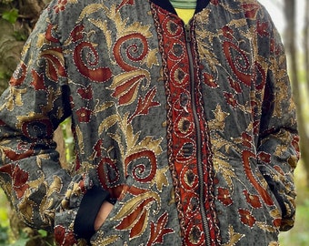 May include: A gray bomber jacket with a floral pattern in shades of red, gold, and brown. The jacket has a zipper closure and a black collar.