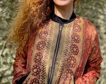 May include: A red bomber jacket with a gold and brown patterned design. The jacket has a zipper closure and two pockets.