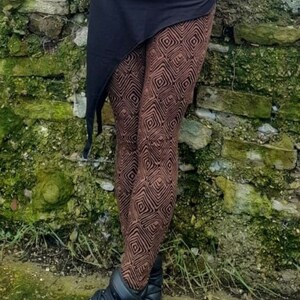 May include: Brown leggings with a geometric pattern and a black asymmetrical skirt. The leggings and skirt are made of a soft, stretchy fabric. The person is wearing black ankle boots.