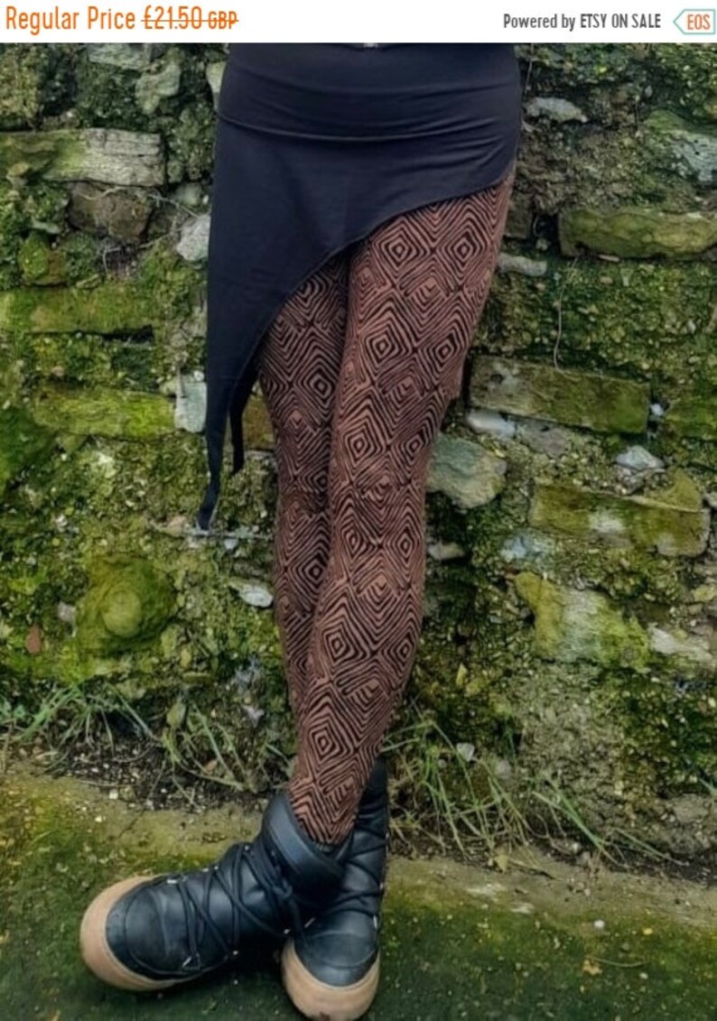 May include: Brown leggings with a geometric pattern and a black asymmetrical skirt. The leggings and skirt are made of a soft, stretchy fabric. The person is wearing black ankle boots.