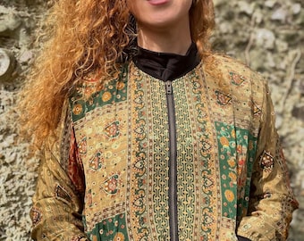 May include: A green and gold patterned bomber jacket with a zipper closure. The jacket has a patchwork design with intricate floral and geometric patterns.
