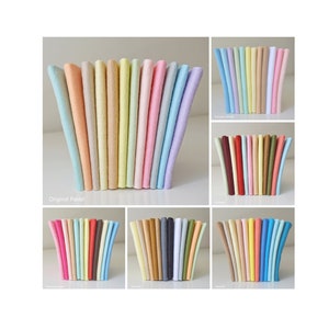 May include: A collection of 10 different colours of felt fabric swatches. The colours are: light blue, light pink, light yellow, light green, light orange, light purple, light brown, light grey, white, and black.