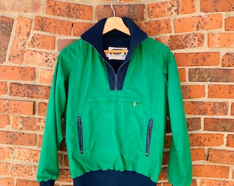 May include: A green and navy blue vintage ski jacket with a zippered pocket and a label that reads "SKI SPORTSWEAR".