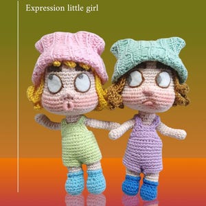 May include: Two crochet dolls with distinct expressions. One doll wears a pink hat, green dungarees, and blue boots. The other doll has a green hat, purple dungarees, and blue boots. The text "Modi Expression little girl" is above the dolls.