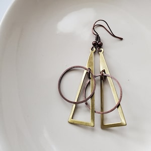 May include: A pair of gold and copper earrings with a triangle and circle design.