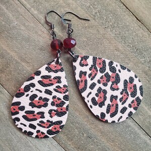 May include: A pair of pink and black leopard print teardrop earrings with red glass beads.