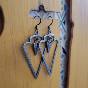 May include: A pair of silver triangle earrings with a hammered texture. The earrings have a simple, modern design and are perfect for everyday wear.