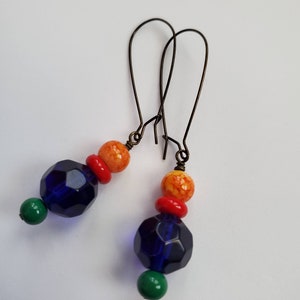 May include: A pair of dangle earrings with blue, orange, and green glass beads. The earrings have a simple wire design.