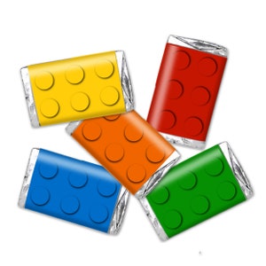 Può includere: Cinque piccole barrette di cioccolato avvolte in foglio di alluminio argentato con disegni stampati colorati che ricordano i mattoncini Lego. I colori sono giallo, rosso, arancio, blu e verde.