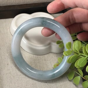 May include: A light green jade bangle bracelet with a smooth, polished finish.
