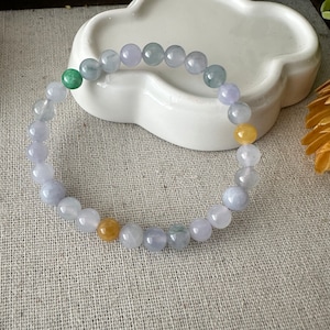 May include: A jade bracelet featuring light blue, green, and yellow beads. The bracelet is crafted from natural jade and is a lovely example of this gemstone.