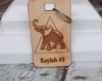 May include: Wooden keychain with a laser-engraved elephant design inside a triangle. The keychain has a silver ring and the text "Kaylah #3" is engraved at the bottom.