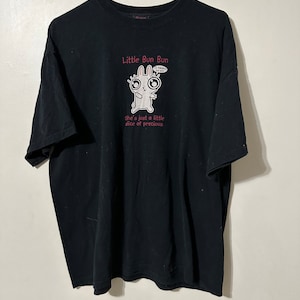 May include: Black t-shirt with a cartoon bunny graphic and the text "Little Bun Bun." The bunny has large eyes and is holding a speech bubble that says "I'm happy 4 you!" The text "She's just a little slice of precious" is below the bunny.