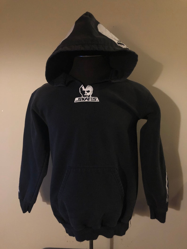 May include: Black hooded sweatshirt with a white skull graphic on the hood and a white skull logo on the front that says "SKATES".